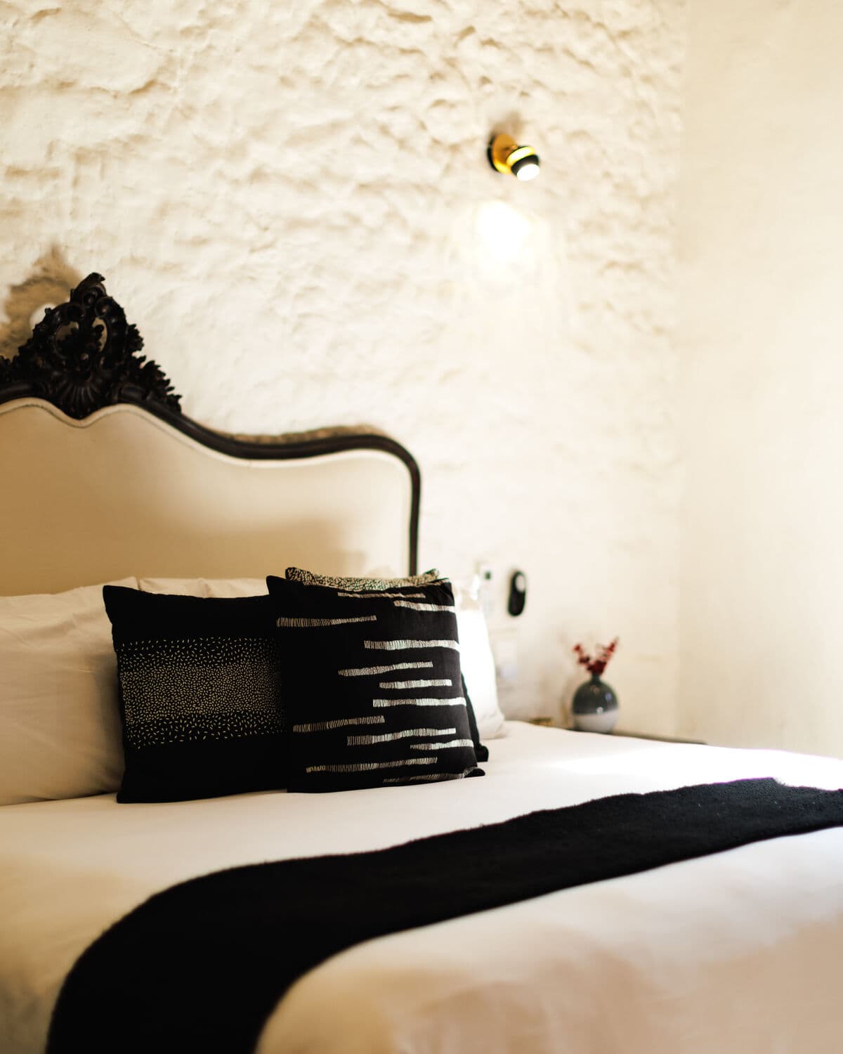 A bedroom in the San Miguel house: a wrought-iron headboard, a woven cushion and a hand-limewashed wall