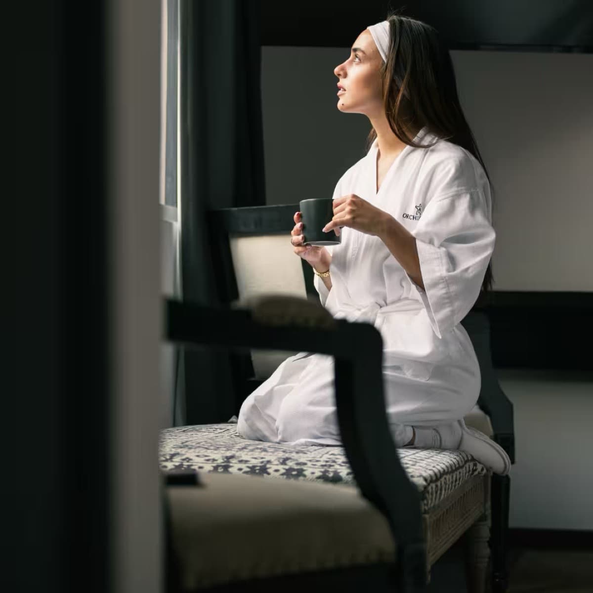 Guest in an Orchid House robe having coffee by the window of their room