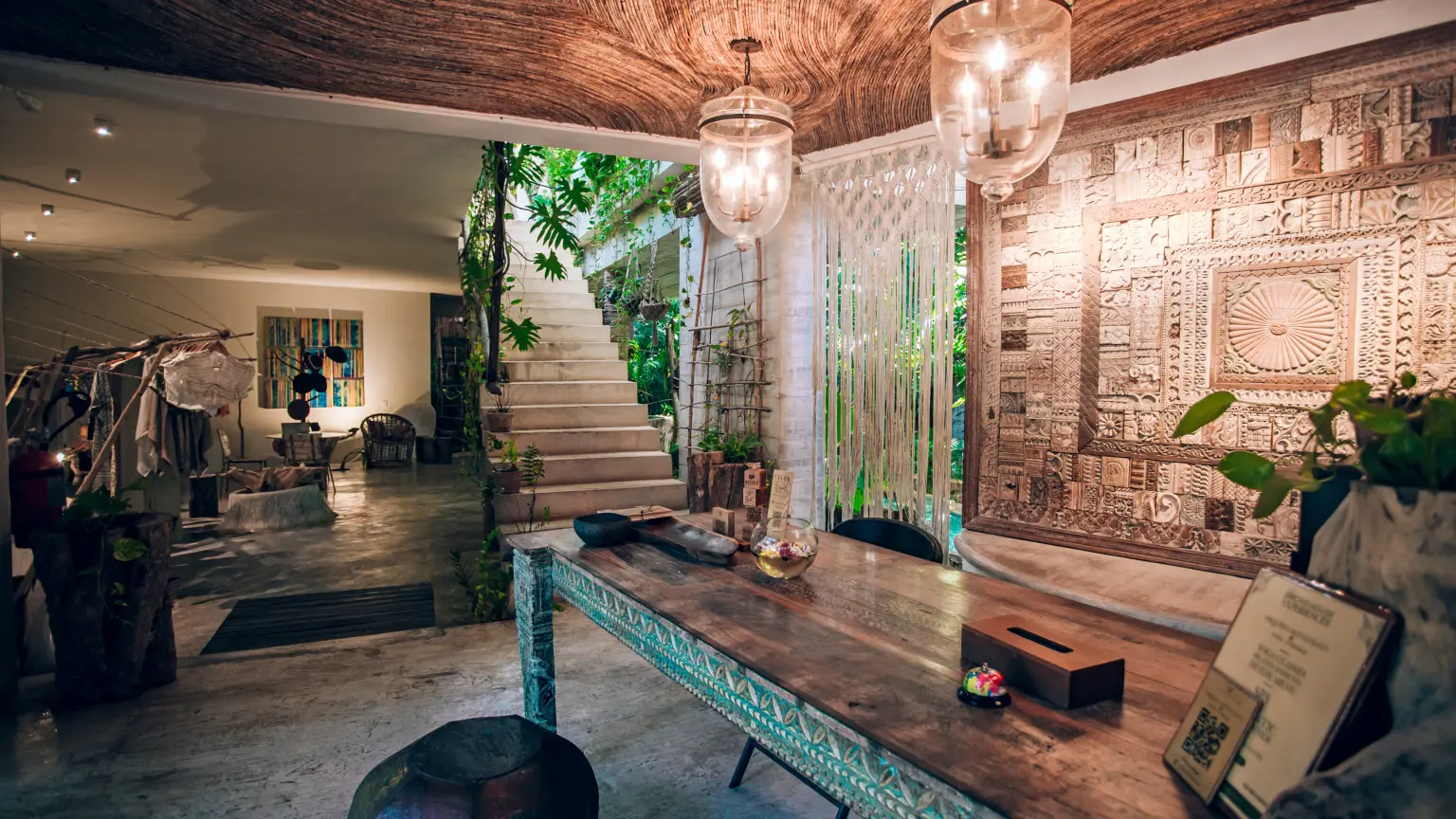 The reception table with turquoise inlay, two hanging glass lanterns and a wall carved with Maya-inspired relief
