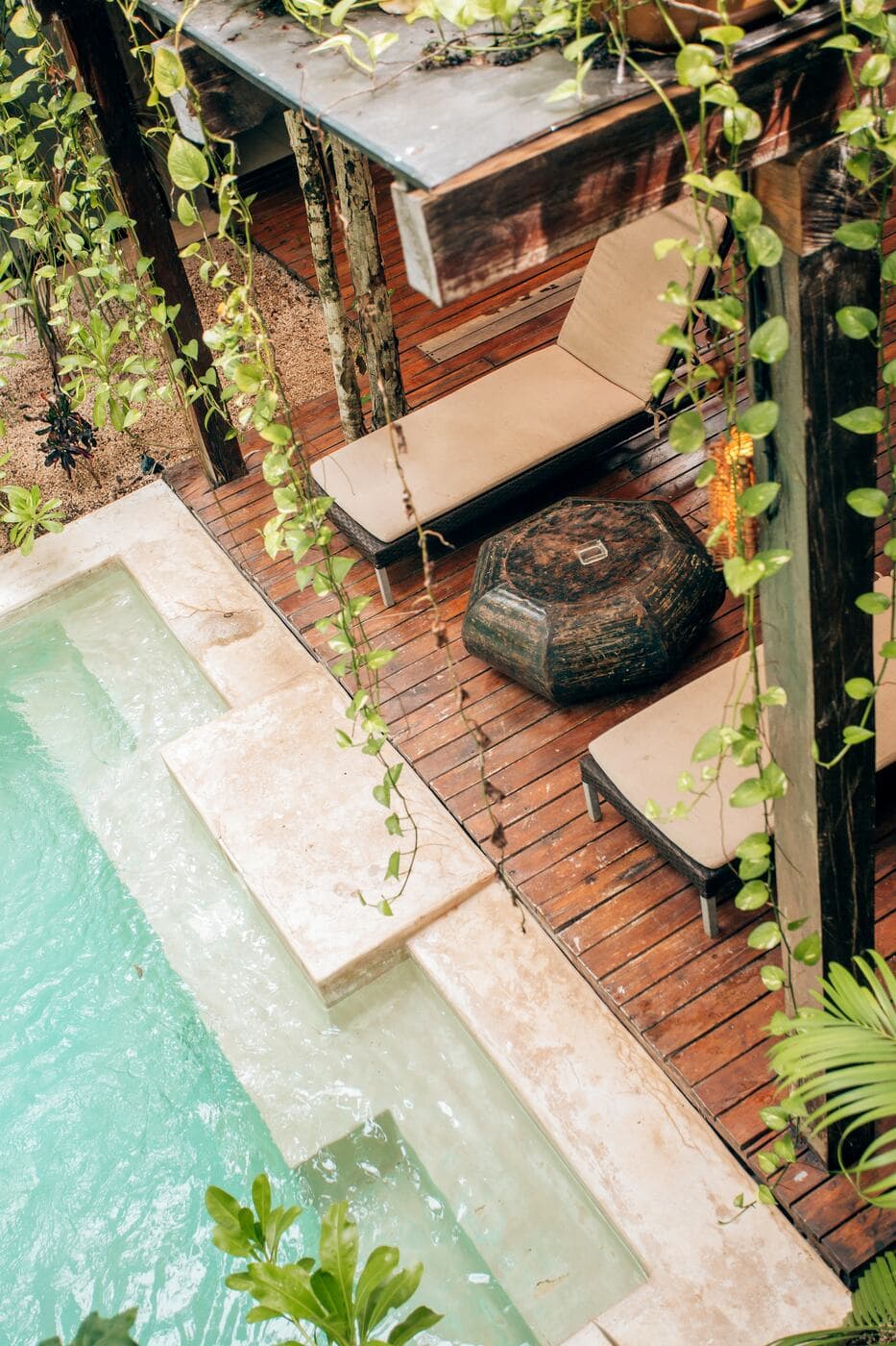 A private plunge pool seen from above, with its brick deck and plants spilling down the wall