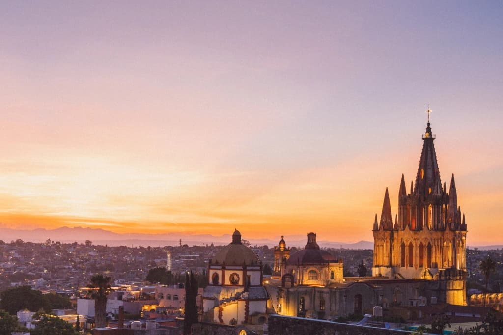 The San Miguel de Allende skyline at sunset, La Parroquia's Gothic spire lit up above the hills