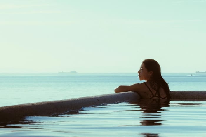 Someone resting on the edge of the infinity pool, looking out at the calm sea