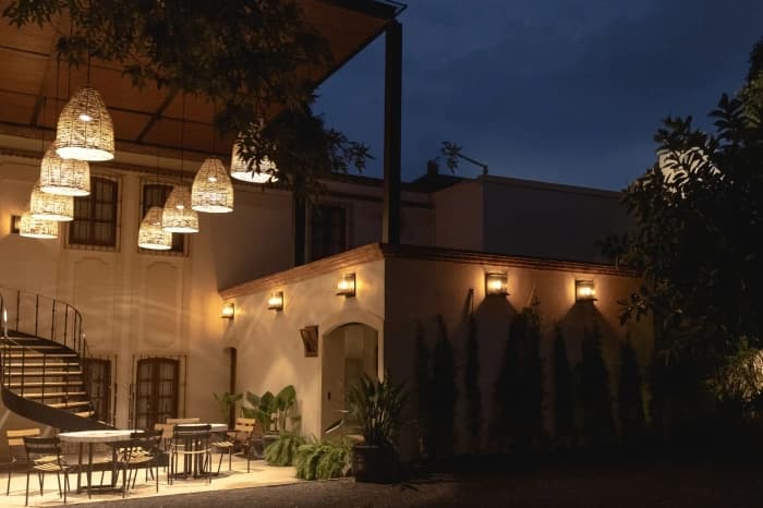 The courtyard at night, wicker lamps hung from the eaves and the façade lit