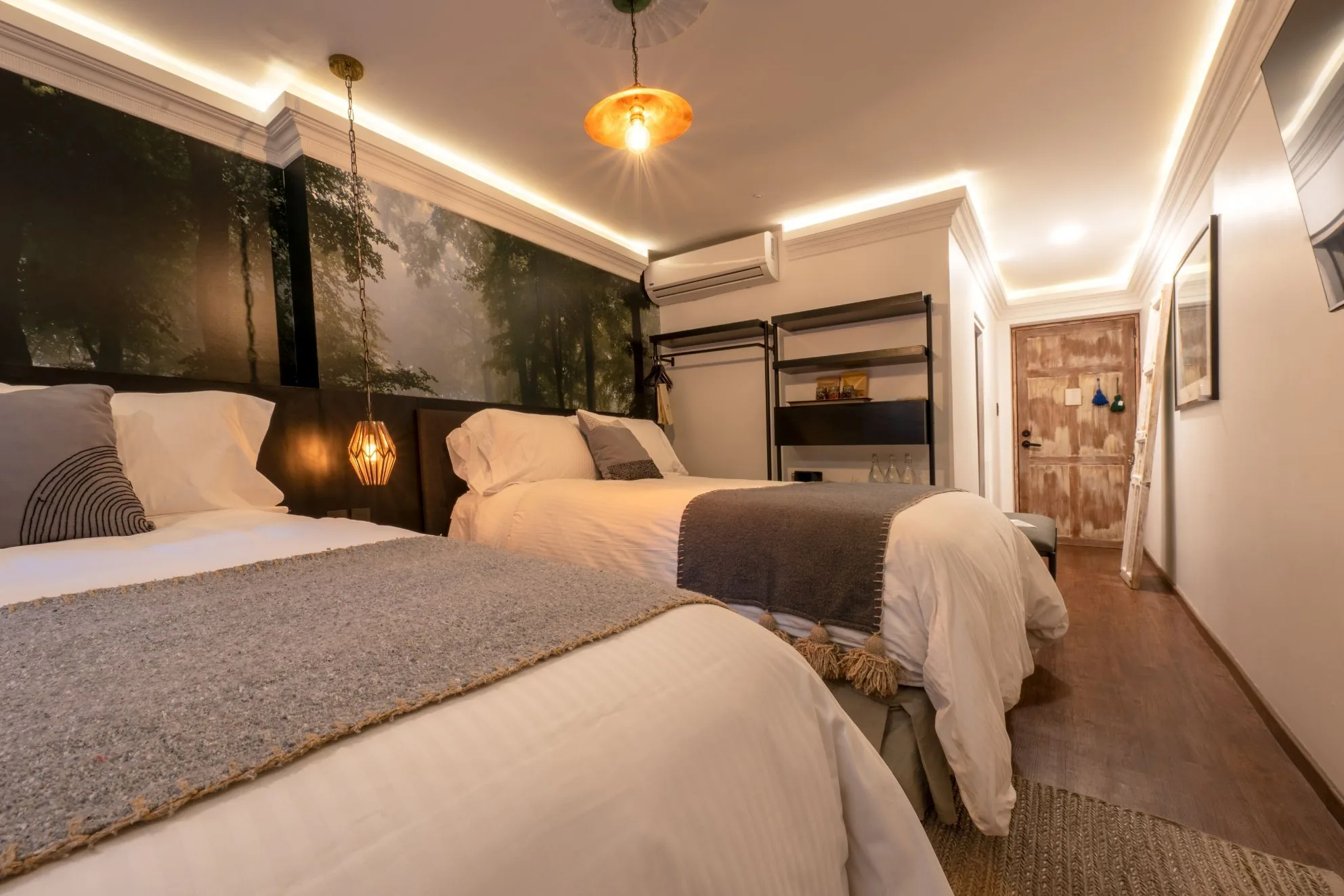 Room with two double beds and a forest photograph as headboard