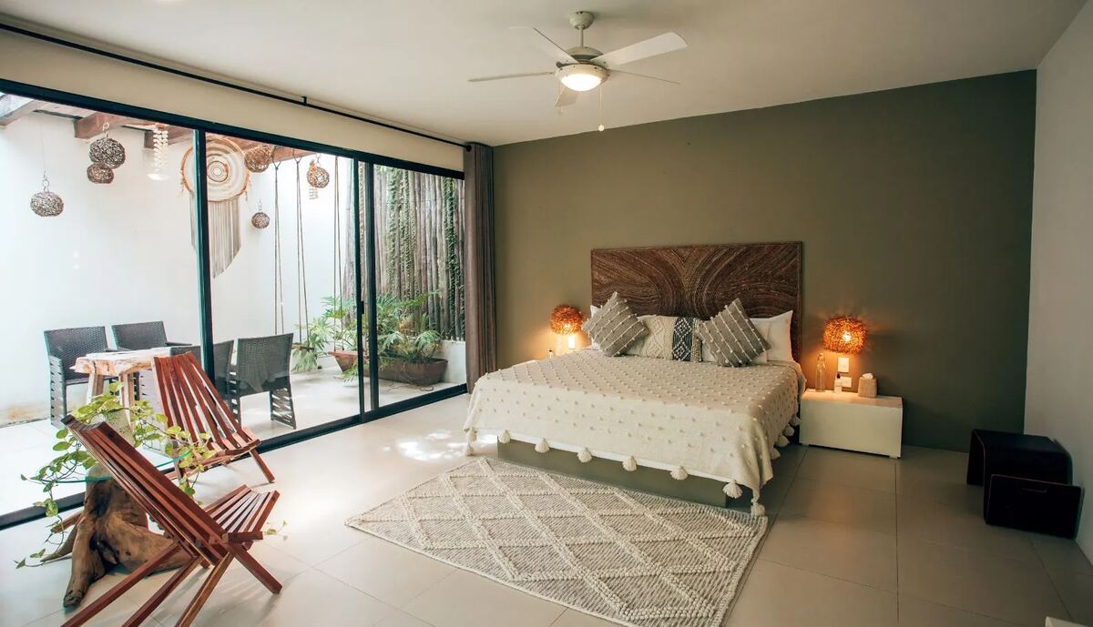 A suite with a carved timber headboard and floor-to-ceiling sliding glass onto the garden