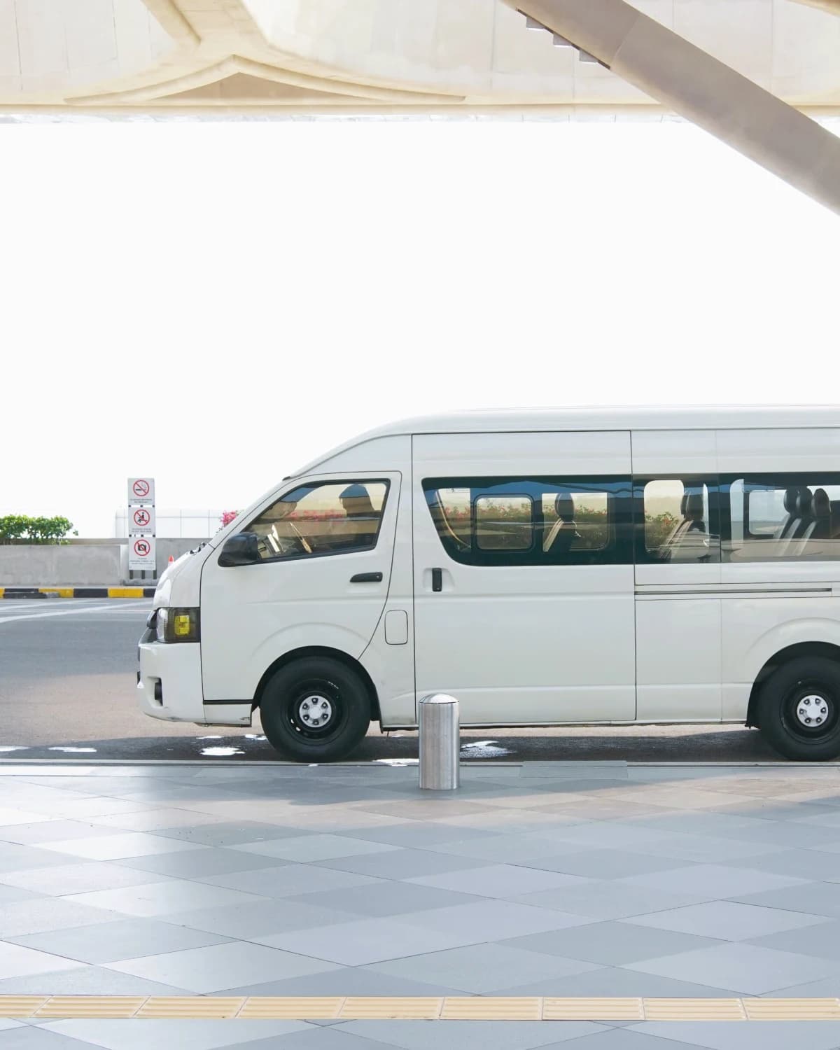 White passenger van parked under the cantilevered roof of a terminal
