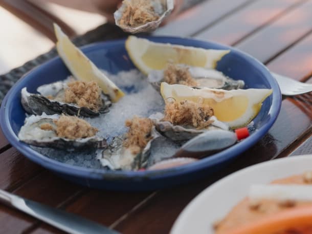 Fresh oysters with lime, served on a blue plate at the wooden tables of El Caimancito