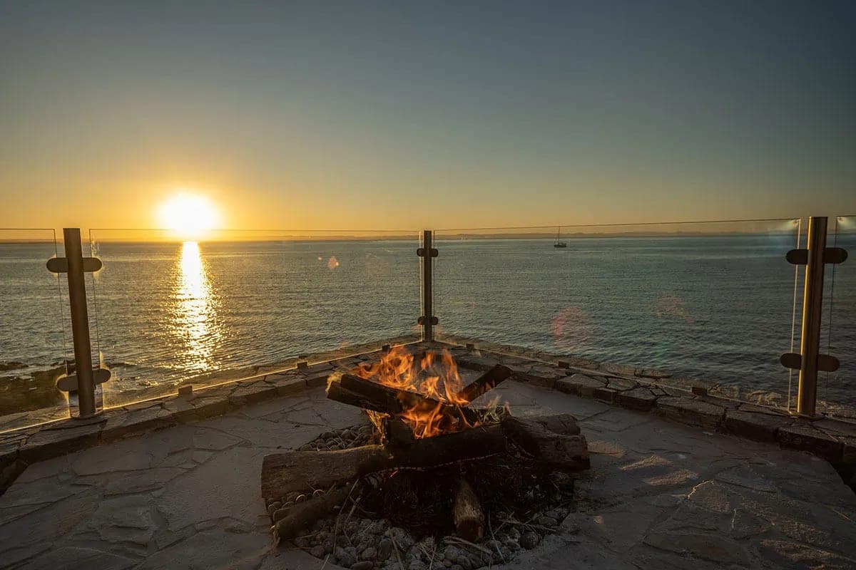 A fire lit on the stone terrace above the water, with the sun setting over the Sea of Cortez