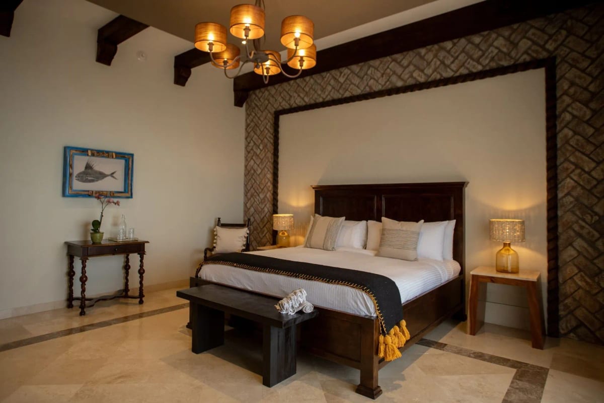 Room with a dark timber king bed, a herringbone brick wall and a framed fish print