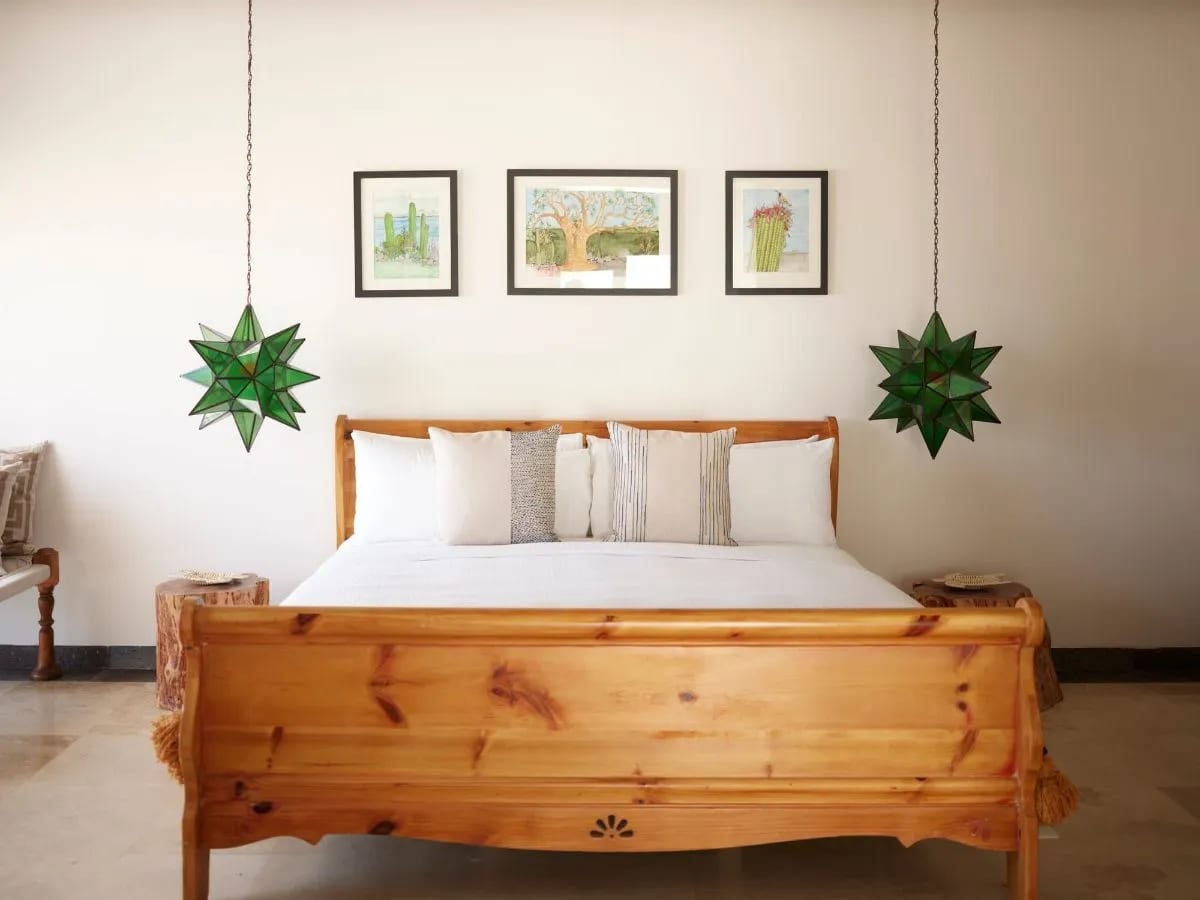 Bedroom in the villa with a timber sleigh bed, green glass star lanterns and framed cactus prints