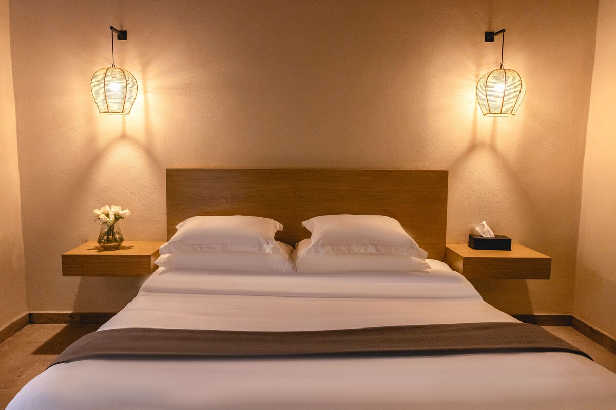 Recámara con cama king sobre base de madera, de líneas limpias y muros lisos