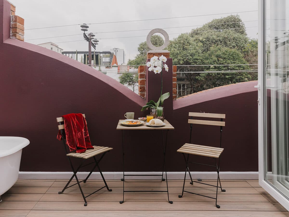 A table set on the rooftop, against the curved wine-coloured wall