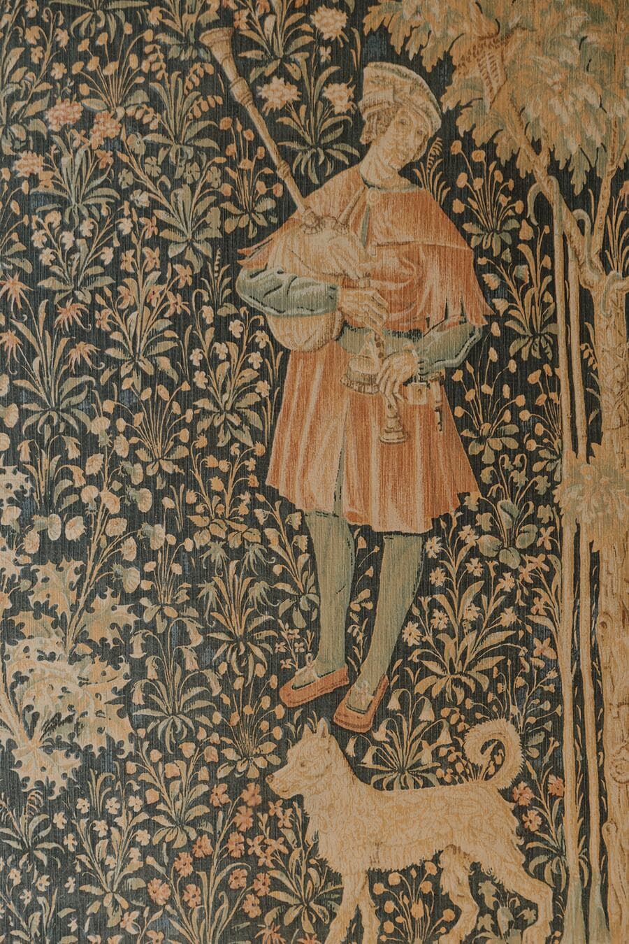 The house's medieval tapestry: a Renaissance figure with a dog, among flowers