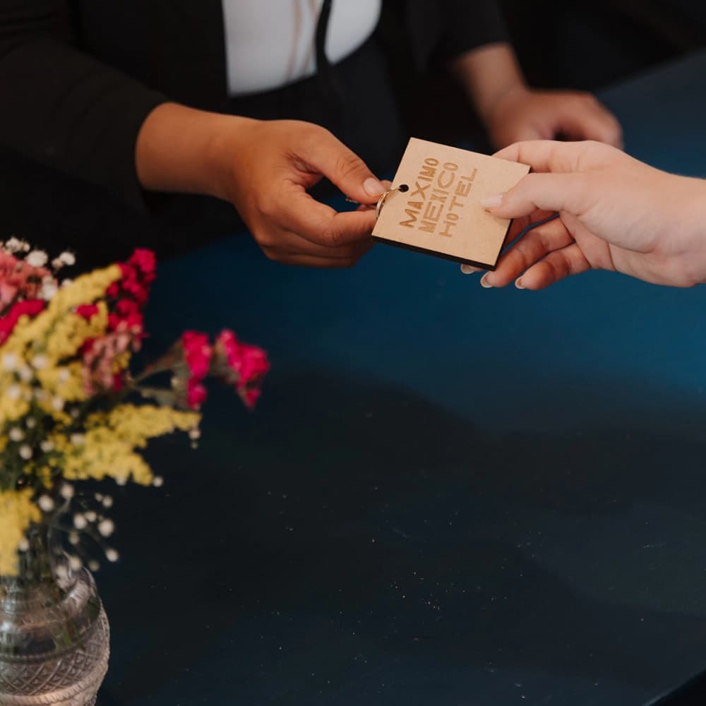 The hotel's engraved wooden key, handed over at the front desk beside a flower arrangement